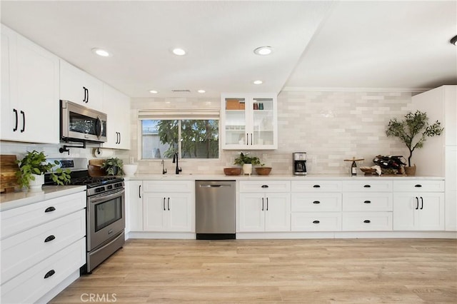 kitchen with white cabinetry, appliances with stainless steel finishes, sink, and light hardwood / wood-style flooring