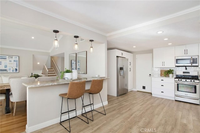 kitchen with appliances with stainless steel finishes, light stone countertops, hanging light fixtures, and white cabinets