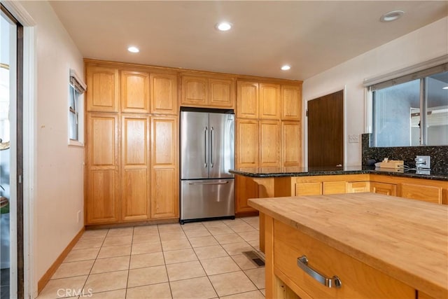 kitchen featuring light tile patterned flooring, wooden counters, stainless steel fridge, and backsplash