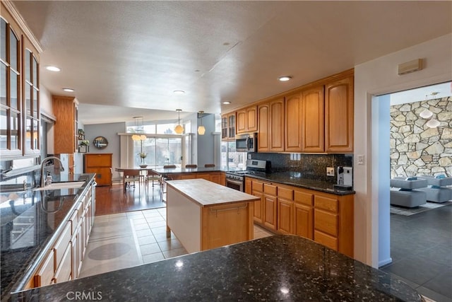 kitchen with a kitchen island, pendant lighting, sink, light tile patterned floors, and stainless steel appliances