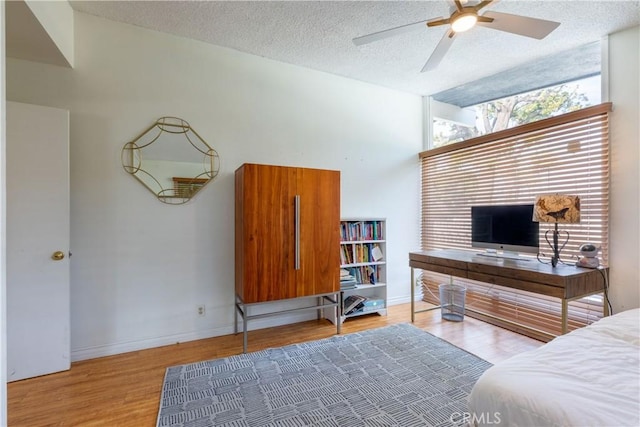 bedroom featuring ceiling fan, light hardwood / wood-style flooring, and a textured ceiling