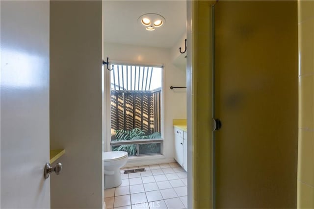 bathroom featuring vanity, toilet, a shower with shower door, and tile patterned flooring