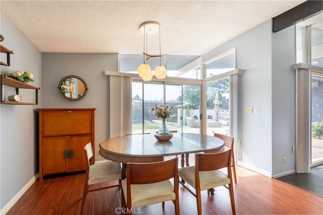 dining room featuring dark wood-type flooring, a chandelier, and a textured ceiling