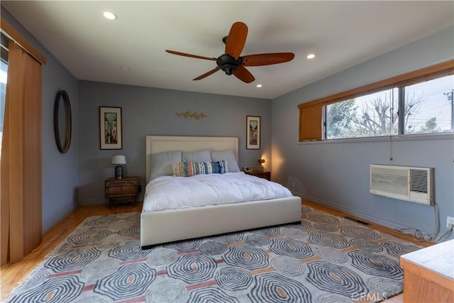 bedroom featuring ceiling fan, light hardwood / wood-style floors, and a wall unit AC