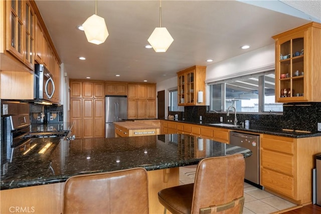 kitchen featuring appliances with stainless steel finishes, decorative light fixtures, sink, and dark stone countertops