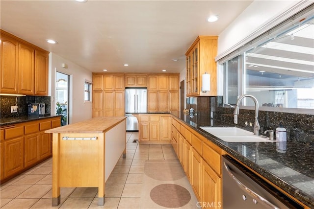 kitchen with light tile patterned flooring, stainless steel appliances, sink, and a kitchen island