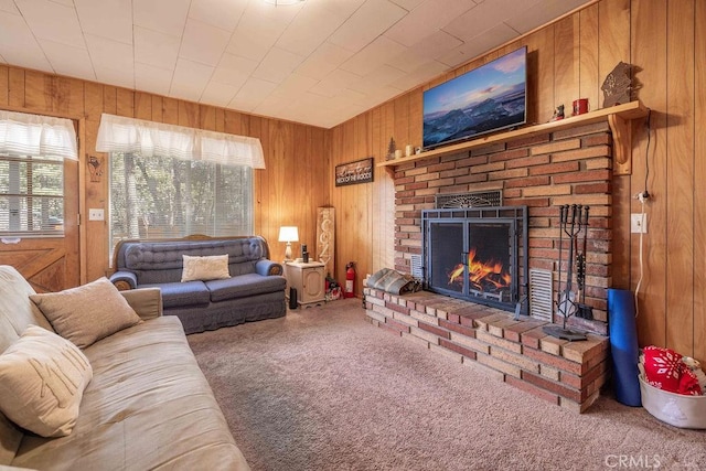 carpeted living room with a fireplace and wood walls