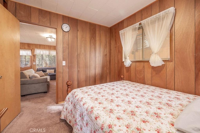 carpeted bedroom featuring wood walls