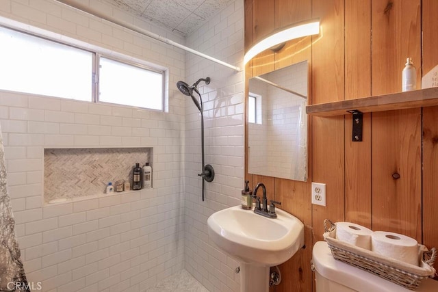 bathroom featuring tiled shower, sink, and toilet