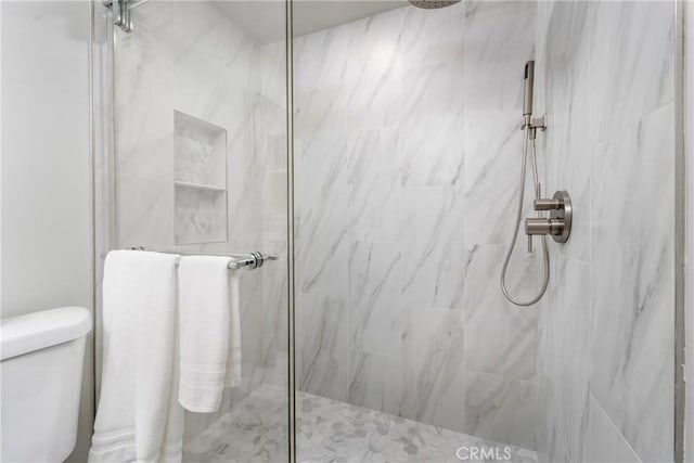 bathroom featuring tiled shower and toilet