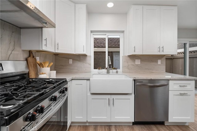 kitchen with sink, premium range hood, white cabinetry, appliances with stainless steel finishes, and light stone countertops