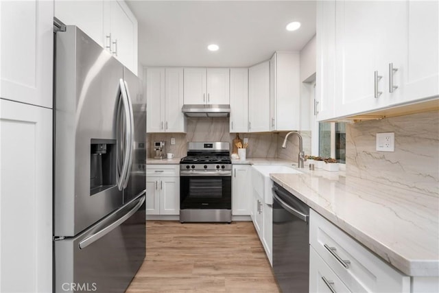 kitchen with sink, appliances with stainless steel finishes, light stone counters, tasteful backsplash, and white cabinets