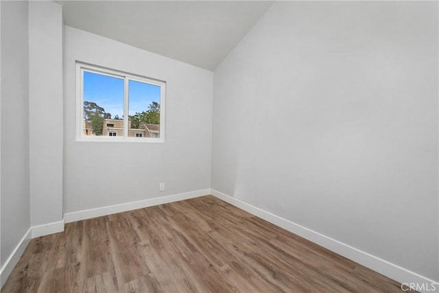 unfurnished room featuring lofted ceiling and light wood-type flooring