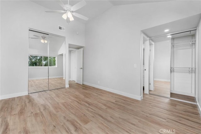 unfurnished bedroom featuring multiple closets, ceiling fan, high vaulted ceiling, and light hardwood / wood-style flooring