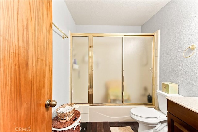 full bathroom featuring hardwood / wood-style flooring, enclosed tub / shower combo, vanity, toilet, and a textured ceiling