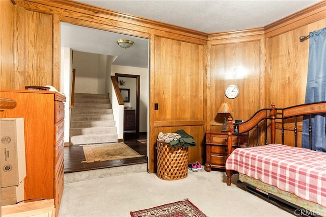 bedroom with light carpet and wood walls