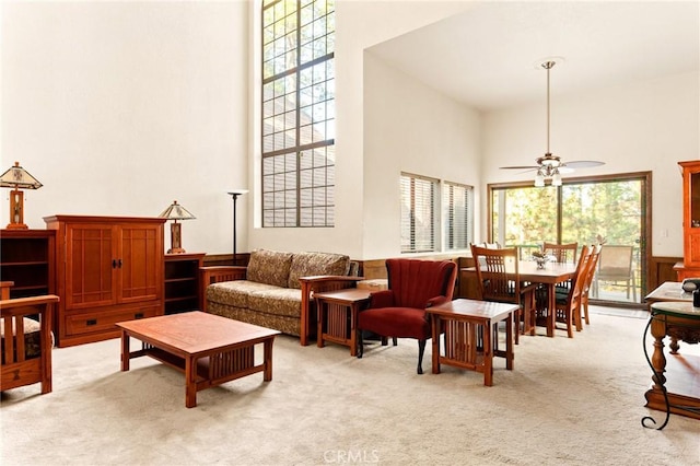 living room with ceiling fan, light carpet, and a high ceiling