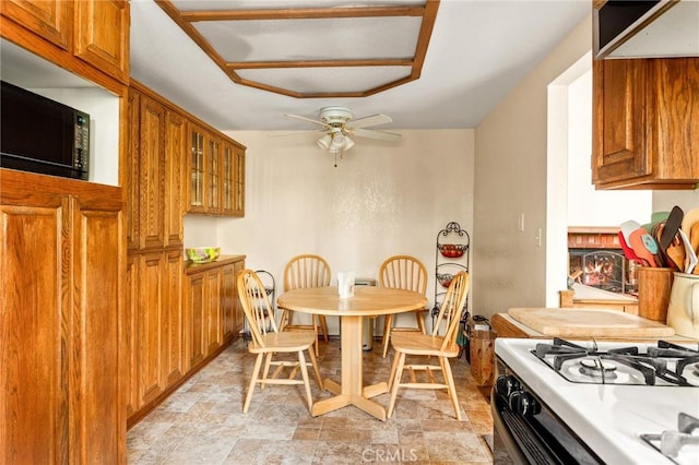 dining space with a brick fireplace and ceiling fan