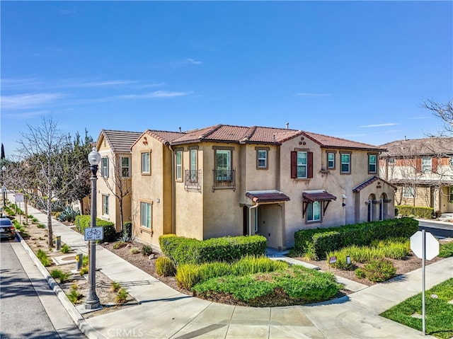 mediterranean / spanish-style house featuring a tiled roof, a residential view, and stucco siding