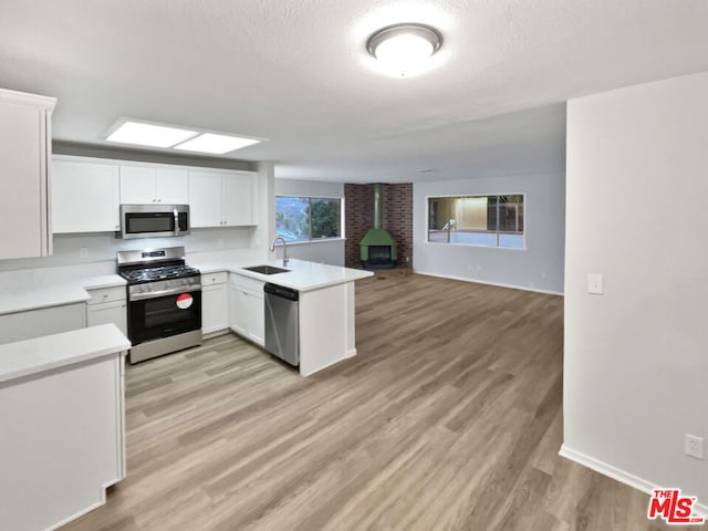 kitchen with white cabinetry, stainless steel appliances, kitchen peninsula, and sink