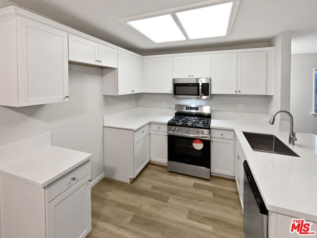 kitchen with sink, light hardwood / wood-style flooring, stainless steel appliances, and white cabinets