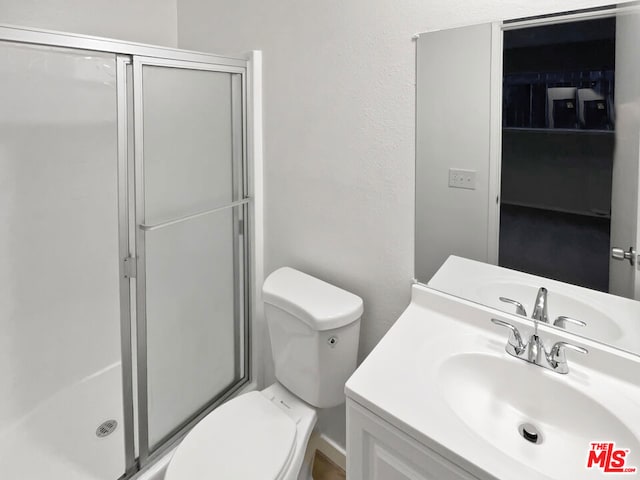 bathroom featuring a shower with door, vanity, and toilet