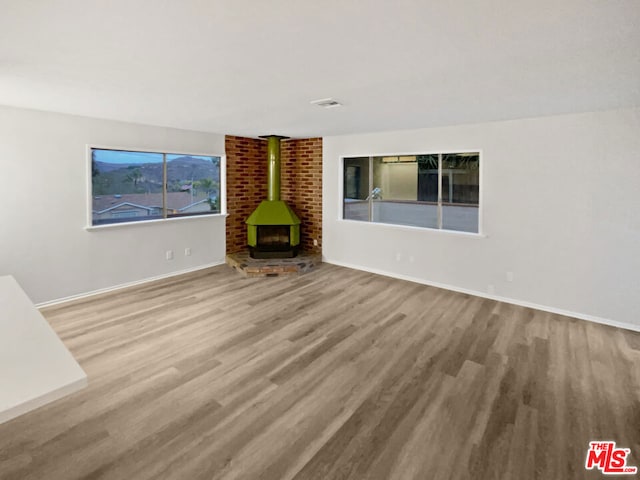 unfurnished living room with a wood stove and light wood-type flooring