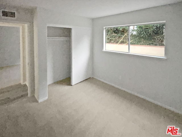 unfurnished bedroom featuring light carpet and a closet