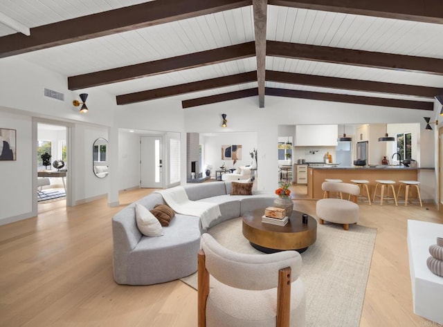 living room featuring vaulted ceiling with beams and light hardwood / wood-style flooring