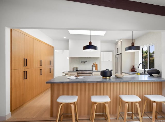 kitchen featuring a breakfast bar, sink, decorative light fixtures, high quality appliances, and kitchen peninsula