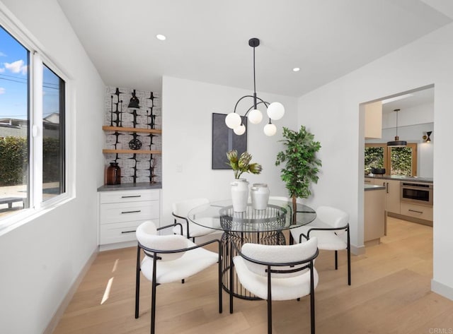 dining room with light hardwood / wood-style floors and a notable chandelier