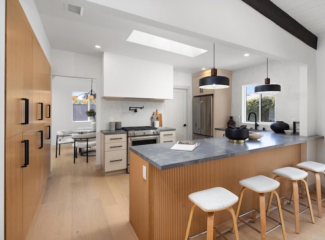 kitchen featuring pendant lighting, appliances with stainless steel finishes, a kitchen breakfast bar, white cabinets, and kitchen peninsula