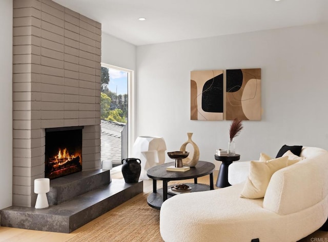 living room featuring wood-type flooring and a brick fireplace