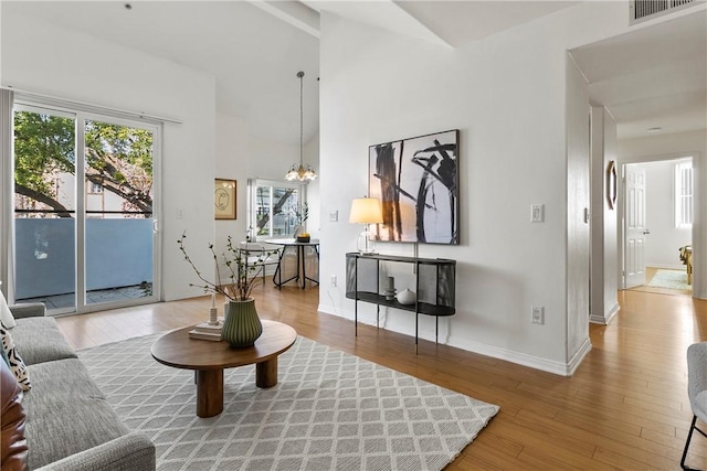 living room with high vaulted ceiling, hardwood / wood-style floors, and a chandelier