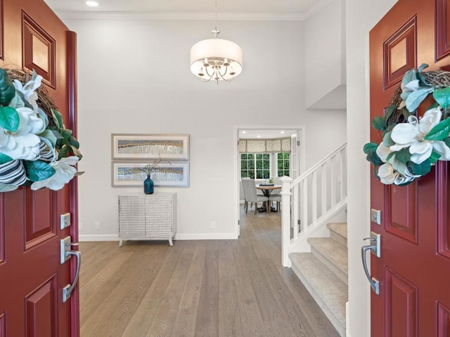 foyer entrance featuring a notable chandelier, crown molding, and light wood-type flooring