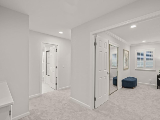 hallway with crown molding and light colored carpet