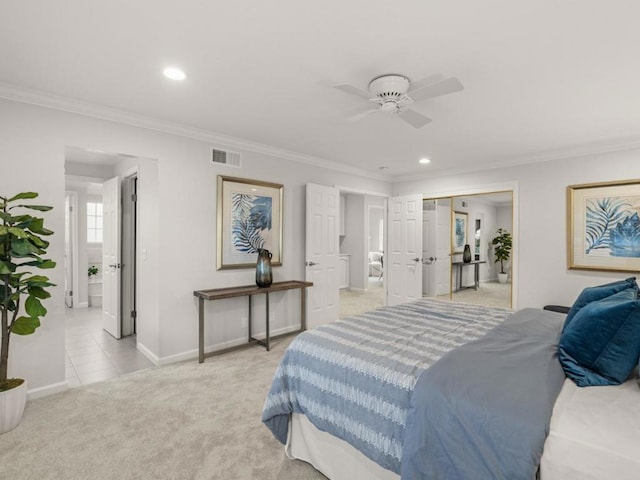 carpeted bedroom with connected bathroom, ornamental molding, and ceiling fan