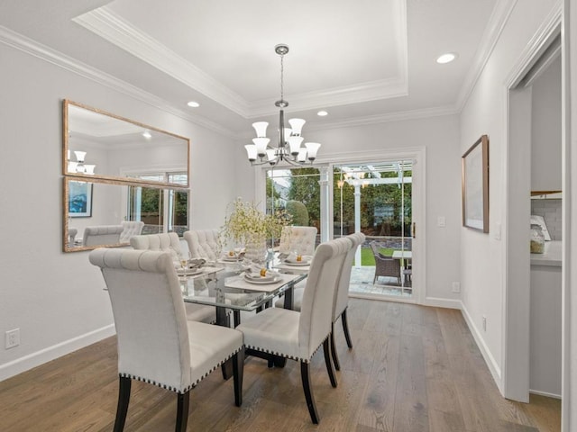 dining area featuring a notable chandelier, a wealth of natural light, a raised ceiling, and wood-type flooring