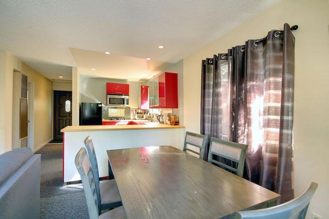 carpeted dining room with a textured ceiling