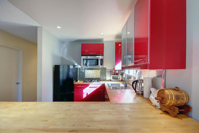 kitchen with butcher block counters, sink, and black appliances