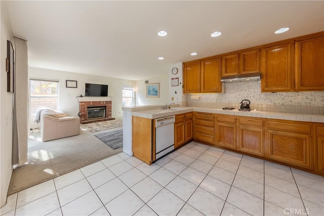 kitchen featuring dishwasher, light colored carpet, brown cabinets, open floor plan, and under cabinet range hood