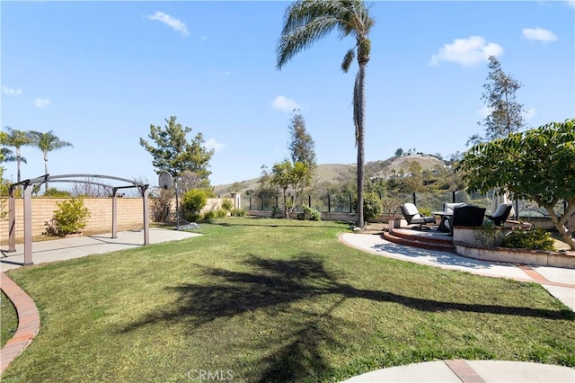 view of yard with fence, a mountain view, and a patio