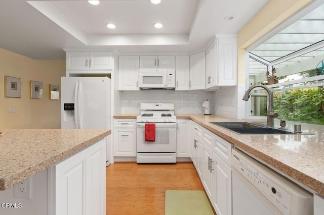 kitchen featuring white appliances, a raised ceiling, sink, and white cabinets