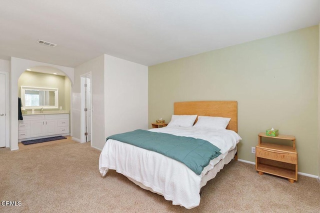 bedroom featuring light carpet and ensuite bath