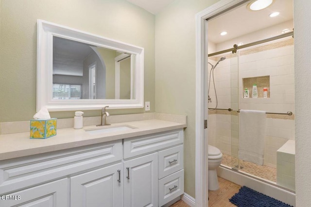 bathroom featuring vanity, toilet, an enclosed shower, and wood-type flooring