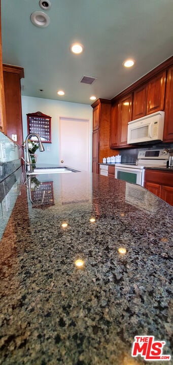 kitchen featuring dark stone countertops, sink, and electric range