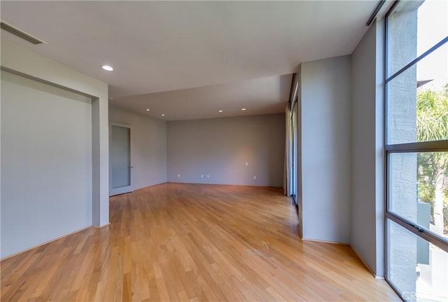 empty room with light hardwood / wood-style flooring, floor to ceiling windows, and a healthy amount of sunlight