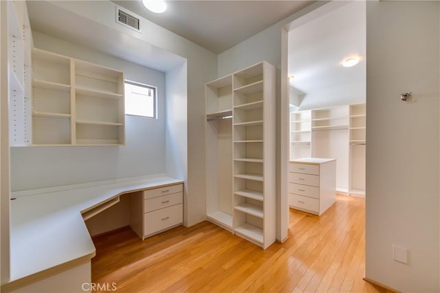 spacious closet featuring built in desk and light wood-type flooring