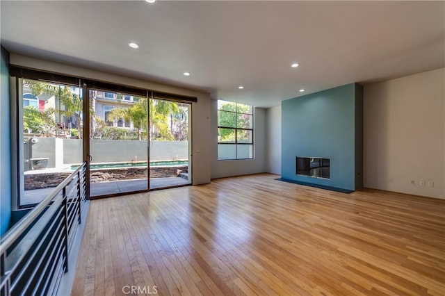 unfurnished living room featuring a multi sided fireplace and light hardwood / wood-style flooring