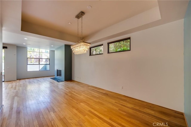 interior space with a chandelier, light hardwood / wood-style floors, and a raised ceiling